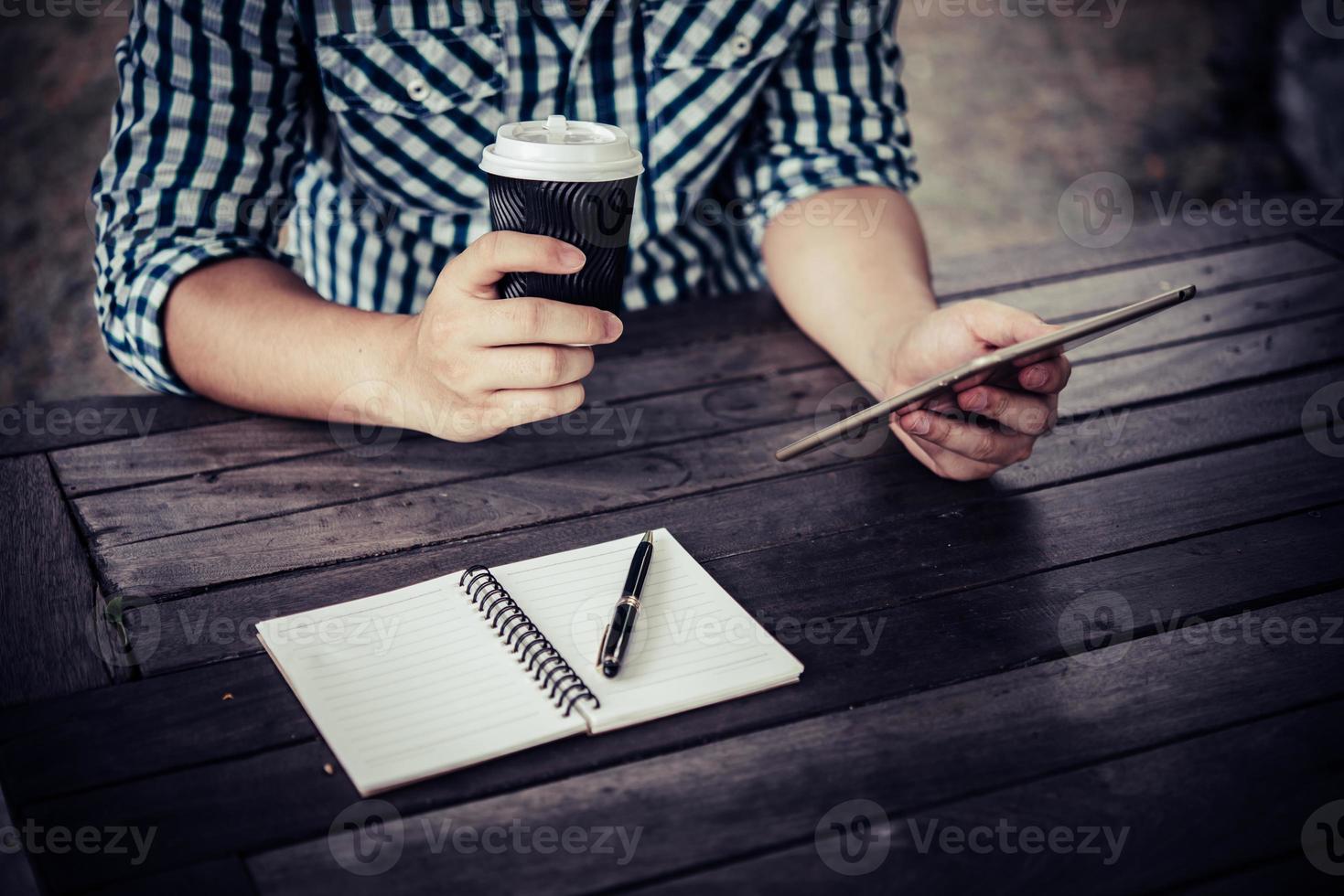 jonge man met behulp van digitale tablet terwijl het drinken van koffie om thuis te zitten tuin foto