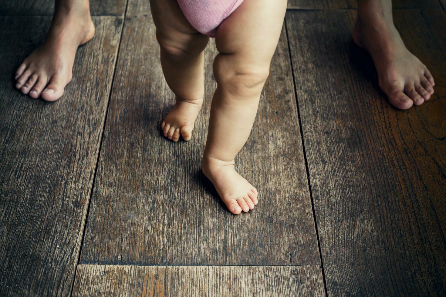 gelukkig baby aan het leren naar wandelen met moeder helpen foto