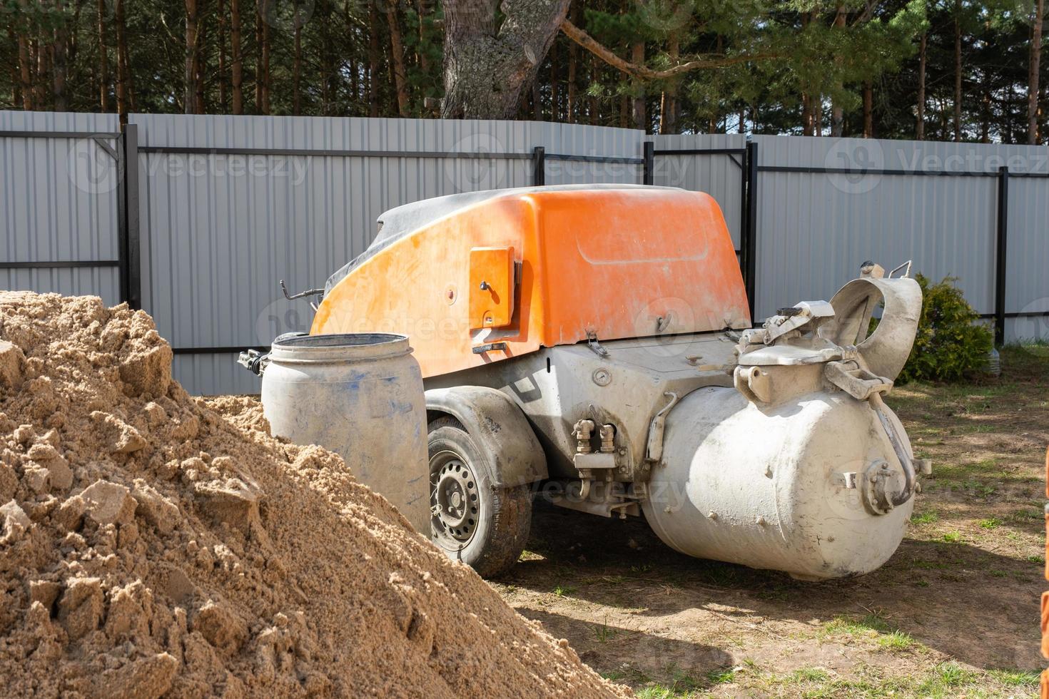 machine met menger isinstallatie voor voeden cement mengsel voor gieten half droog verdieping dekvloer in huis. bouw plaats met glijbaan van zand, voorbereiding voor nivelleren de ruw verdieping van huisje foto