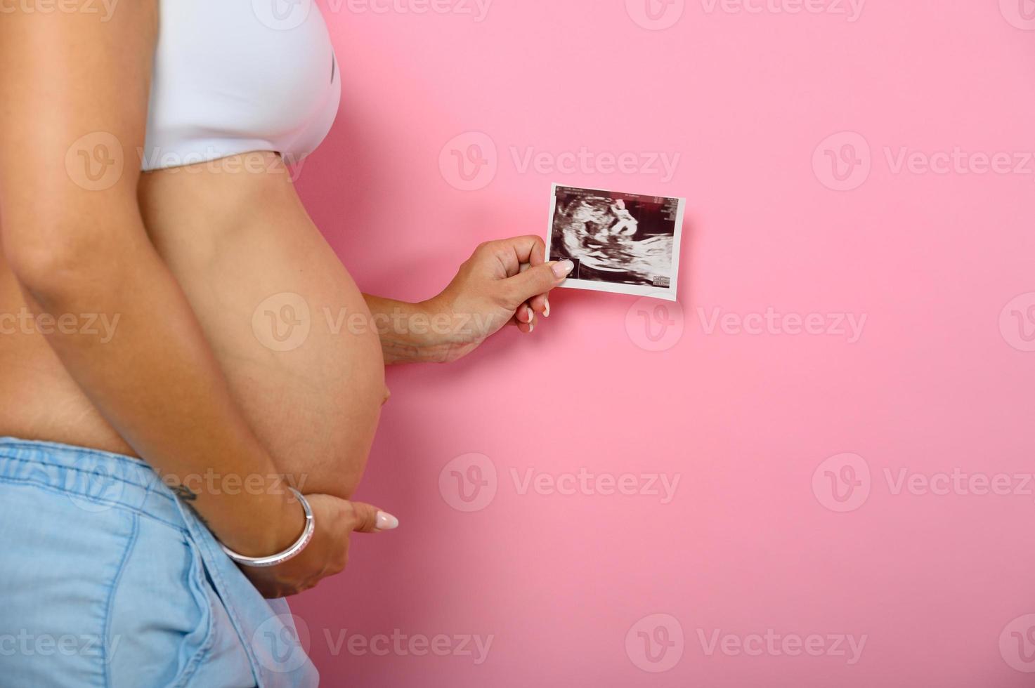 zwanger mam shows een echografie van haar zoon foto