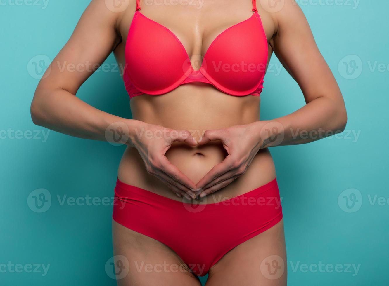 sport vrouw in lingerie maken een hart vorm met handen. cyaan achtergrond foto