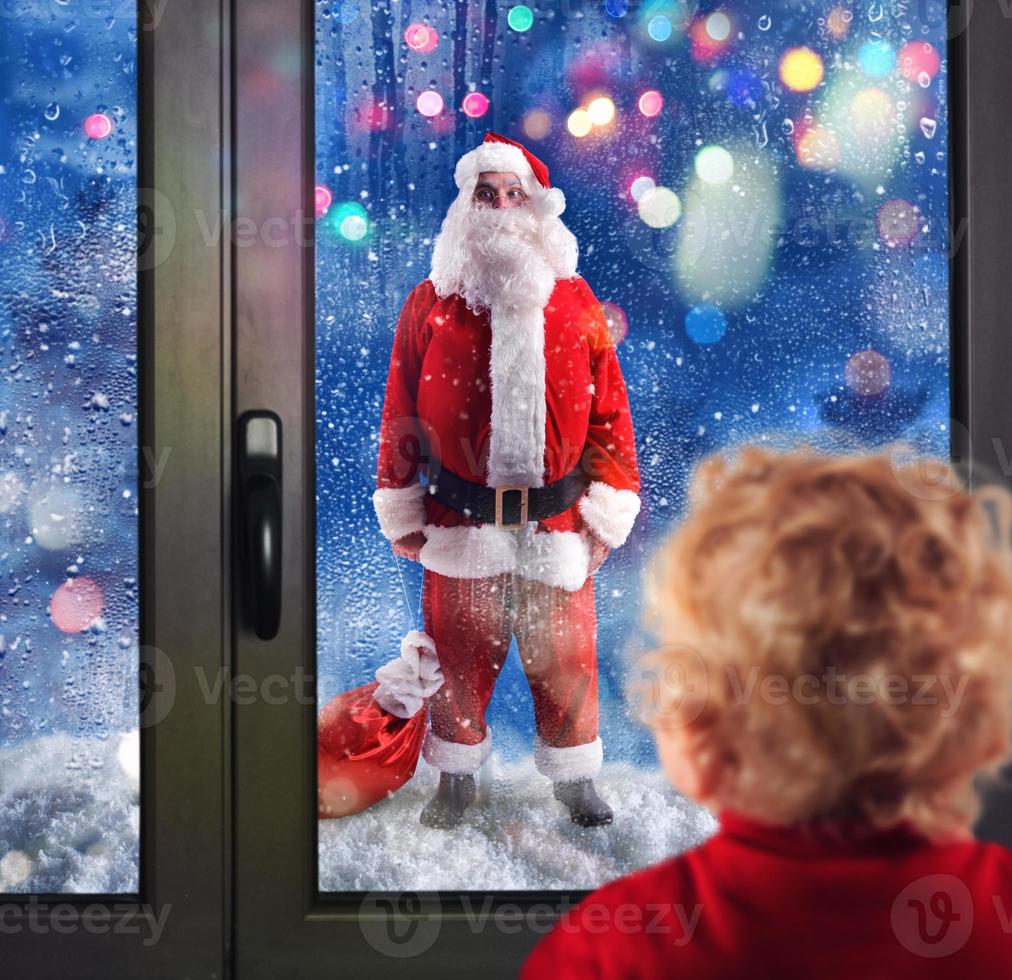 kind merkt op de kerstman claus door de ramen foto