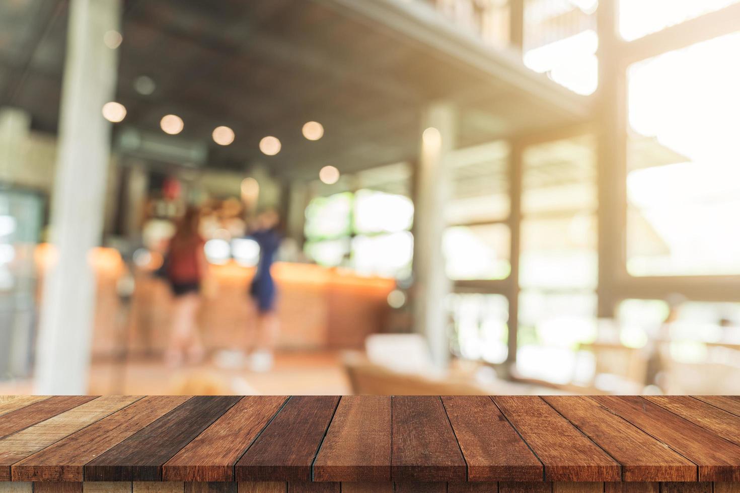 leeg hout tafel en wazig achtergrond klant Bij koffie winkel vervagen achtergrond met bokeh, Scherm montage voor Product. foto