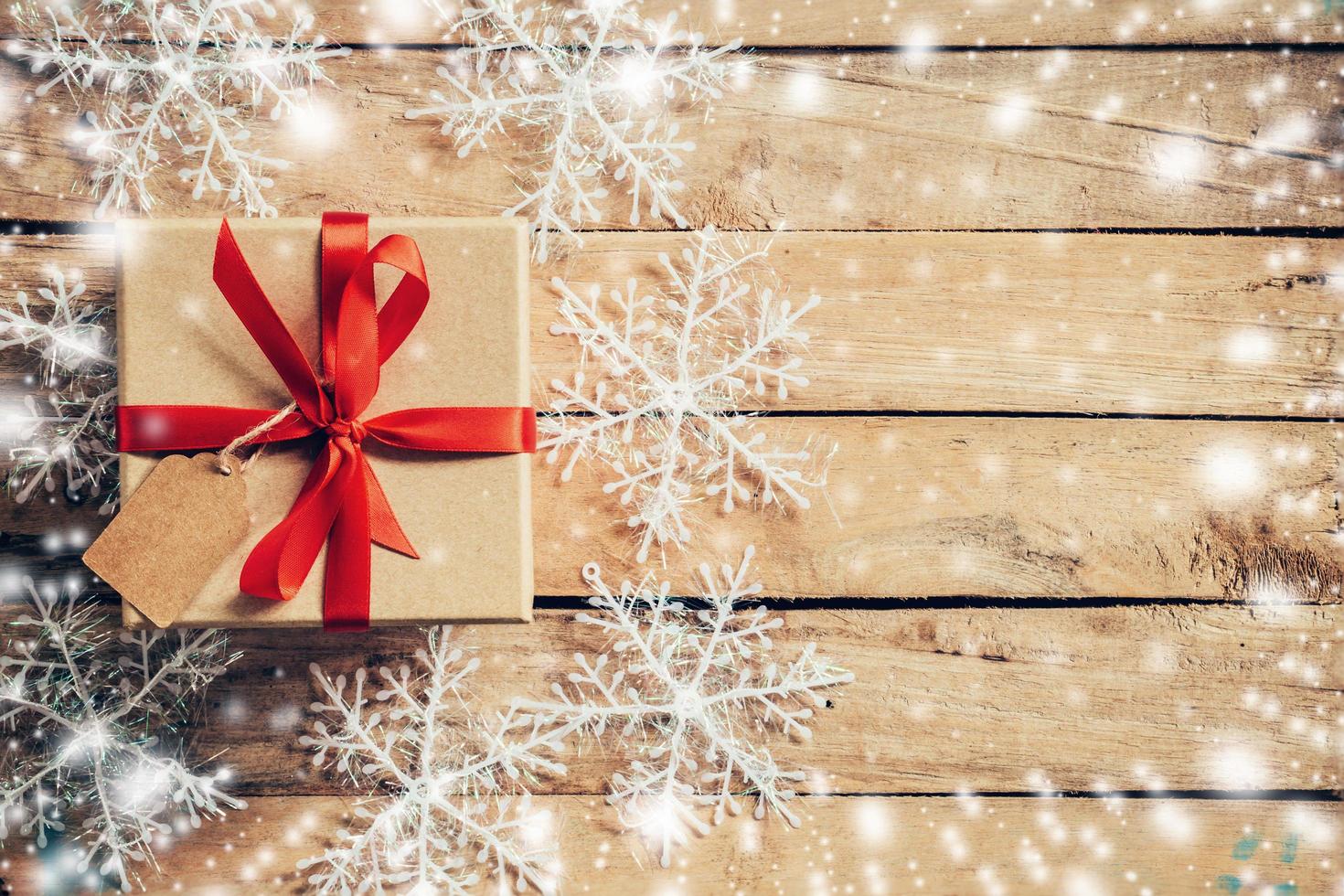 geschenk doos en Kerstmis decoratie en sneeuw met wit sneeuwvlokken Aan houten planken, kopiëren ruimte. foto