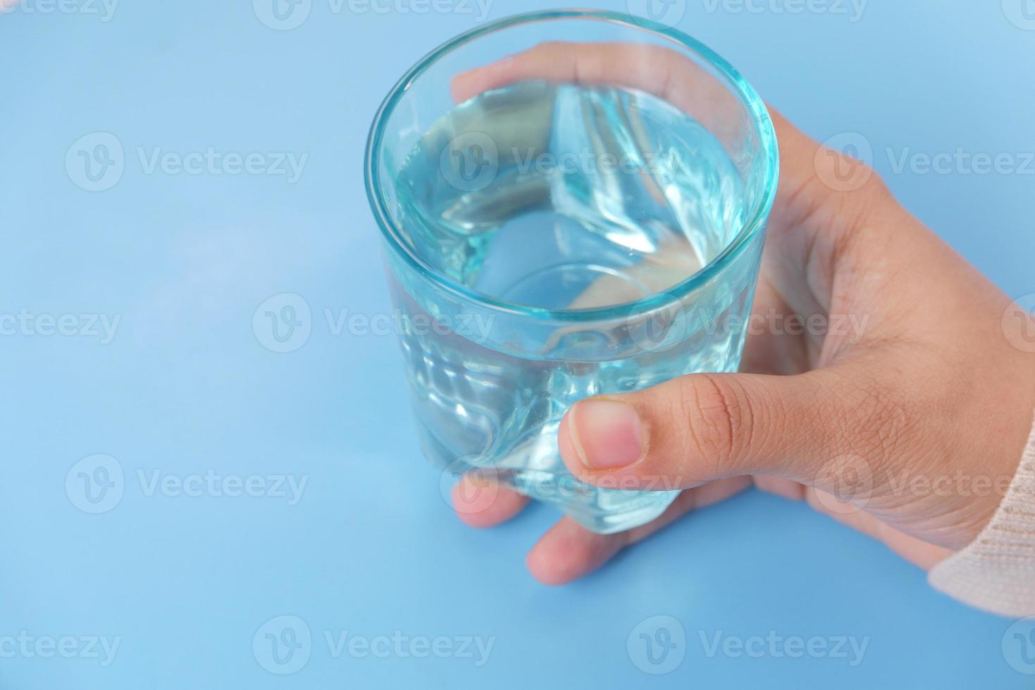 hand met een blauw glas op een blauwe achtergrond foto