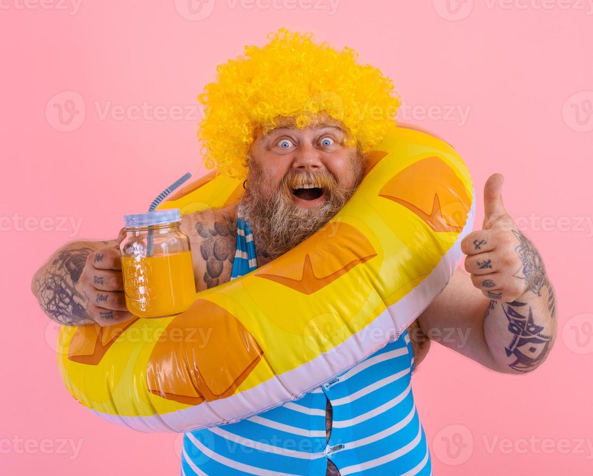 dik gelukkig Mens met pruik in hoofd is klaar naar zwemmen met een donut redder in nood foto