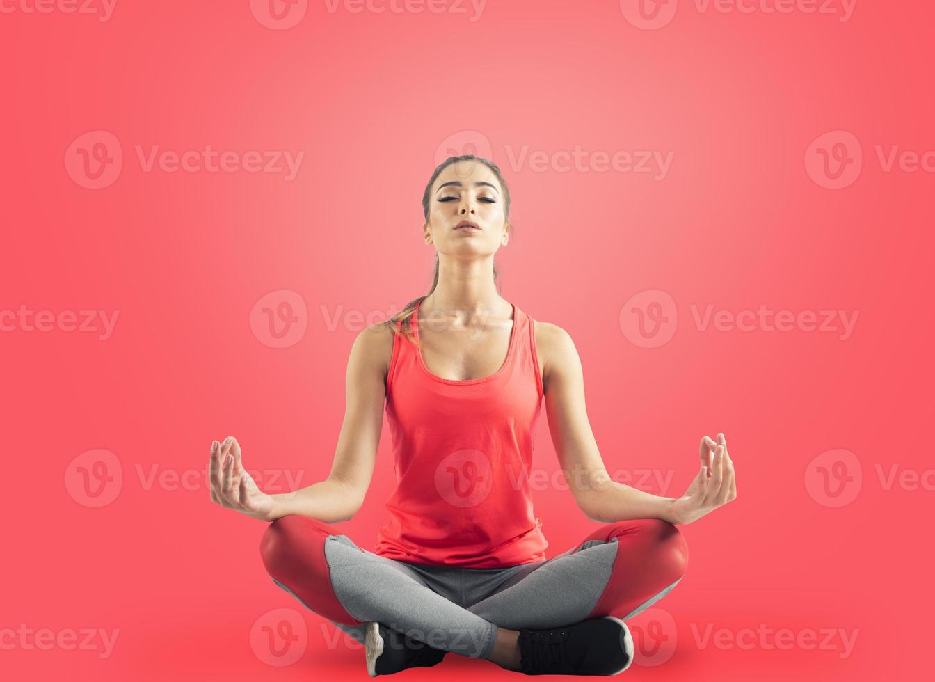 jong meisje ontspannende in yoga positie Aan rood achtergrond foto