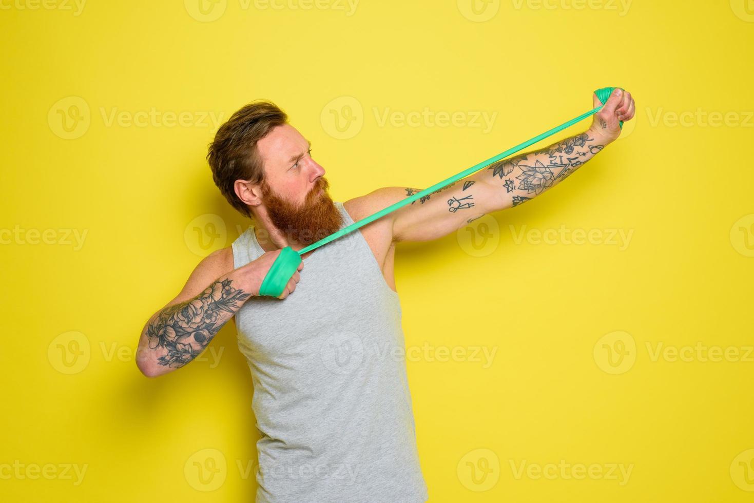 Mens met baard en tatoeages treinen met een rubber band foto