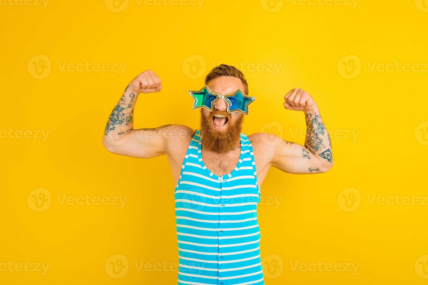 Mens met baard, tatoeages en zwempak shows zijn spier foto