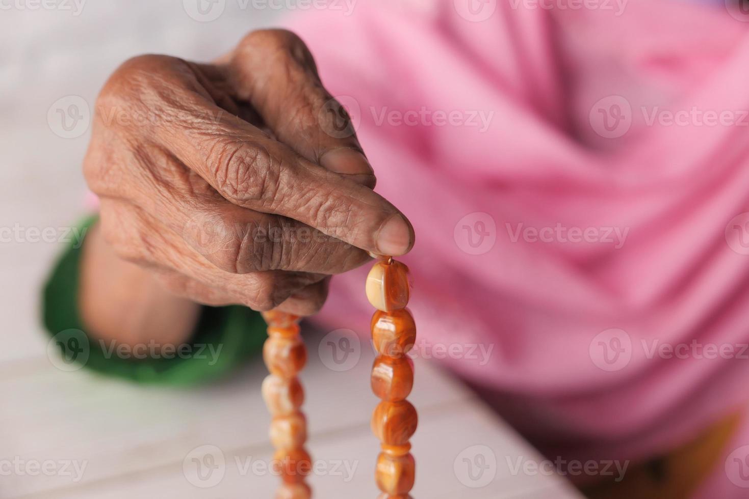 de hand van de oude vrouw met gebedskralen foto