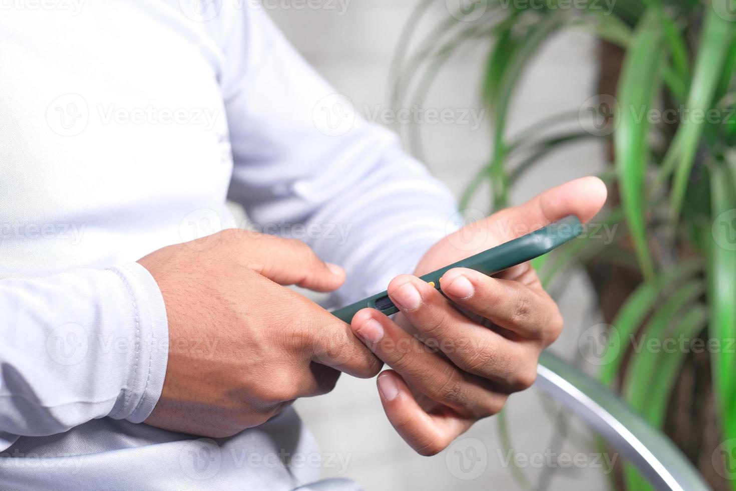 man zittend in stoel met behulp van slimme telefoon foto