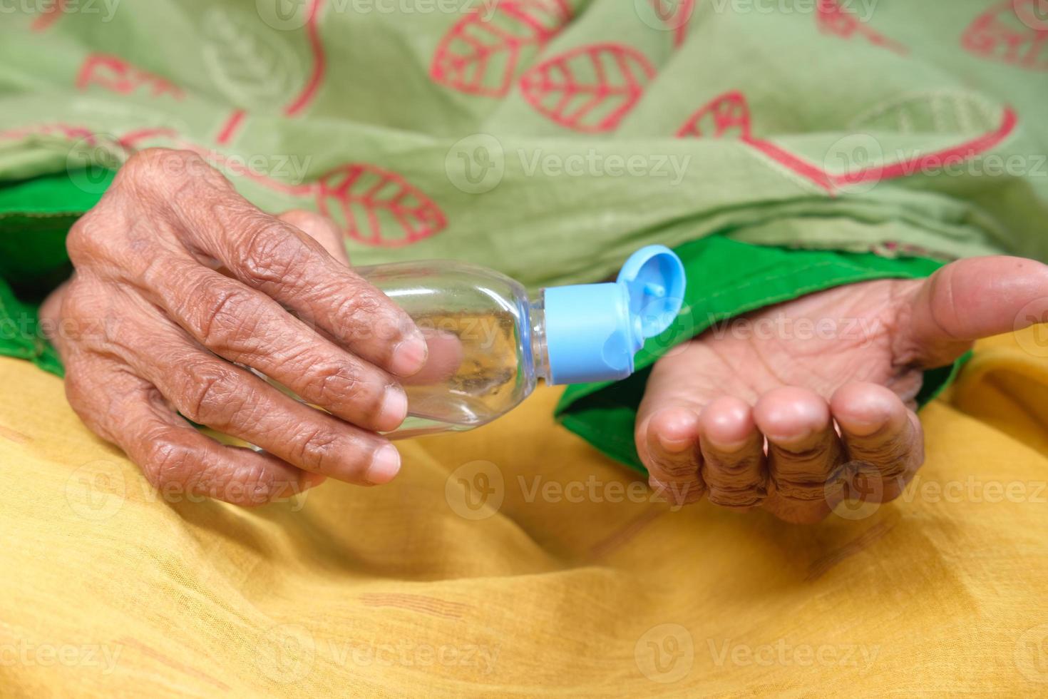 oude vrouw die handdesinfecterend middel gebruikt foto
