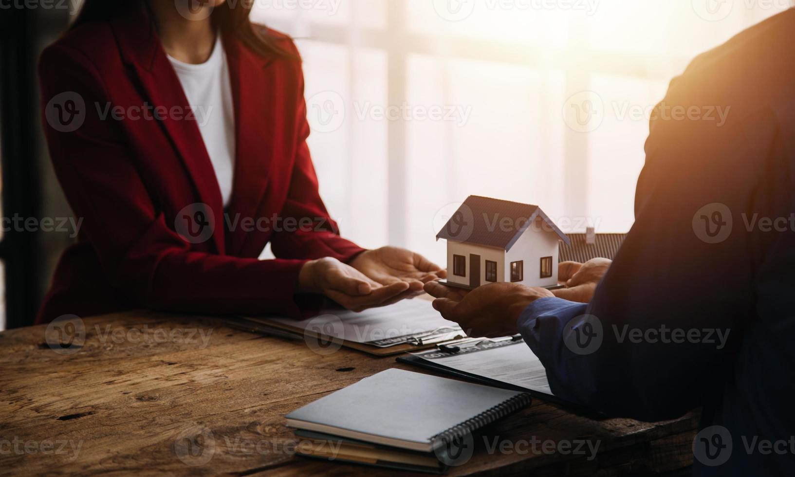 makelaar in onroerend goed presenteren en overleggen met klant bij besluitvorming ondertekenen verzekeringsformulier overeenkomst, kopen en verkopen huismodel, met betrekking tot hypothecaire lening en woningverzekering foto