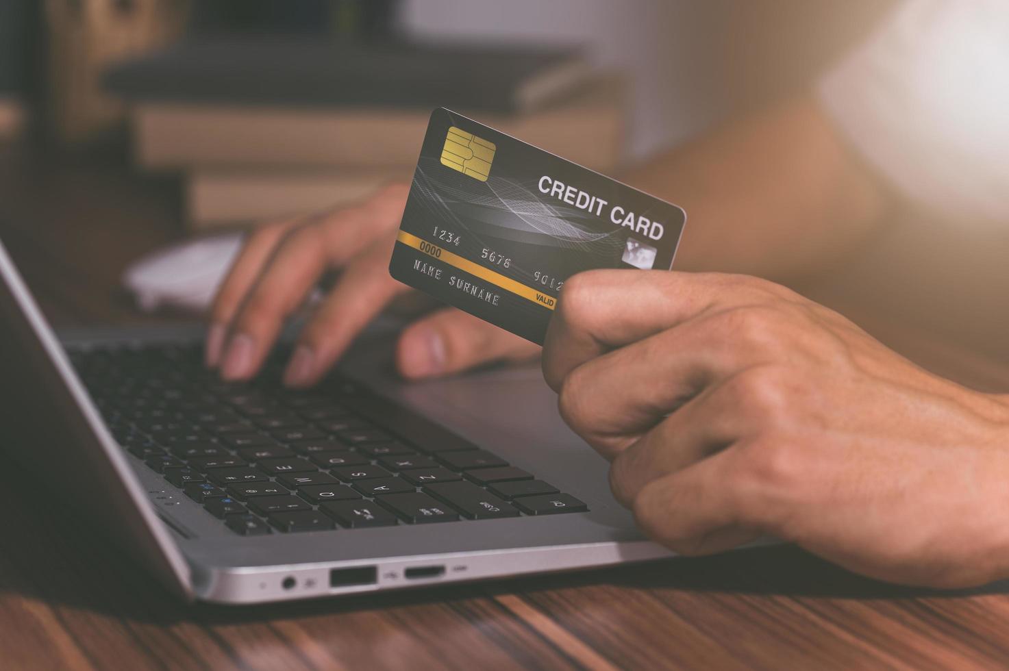 persoon die een creditcard gebruikt om online te winkelen via de computer foto