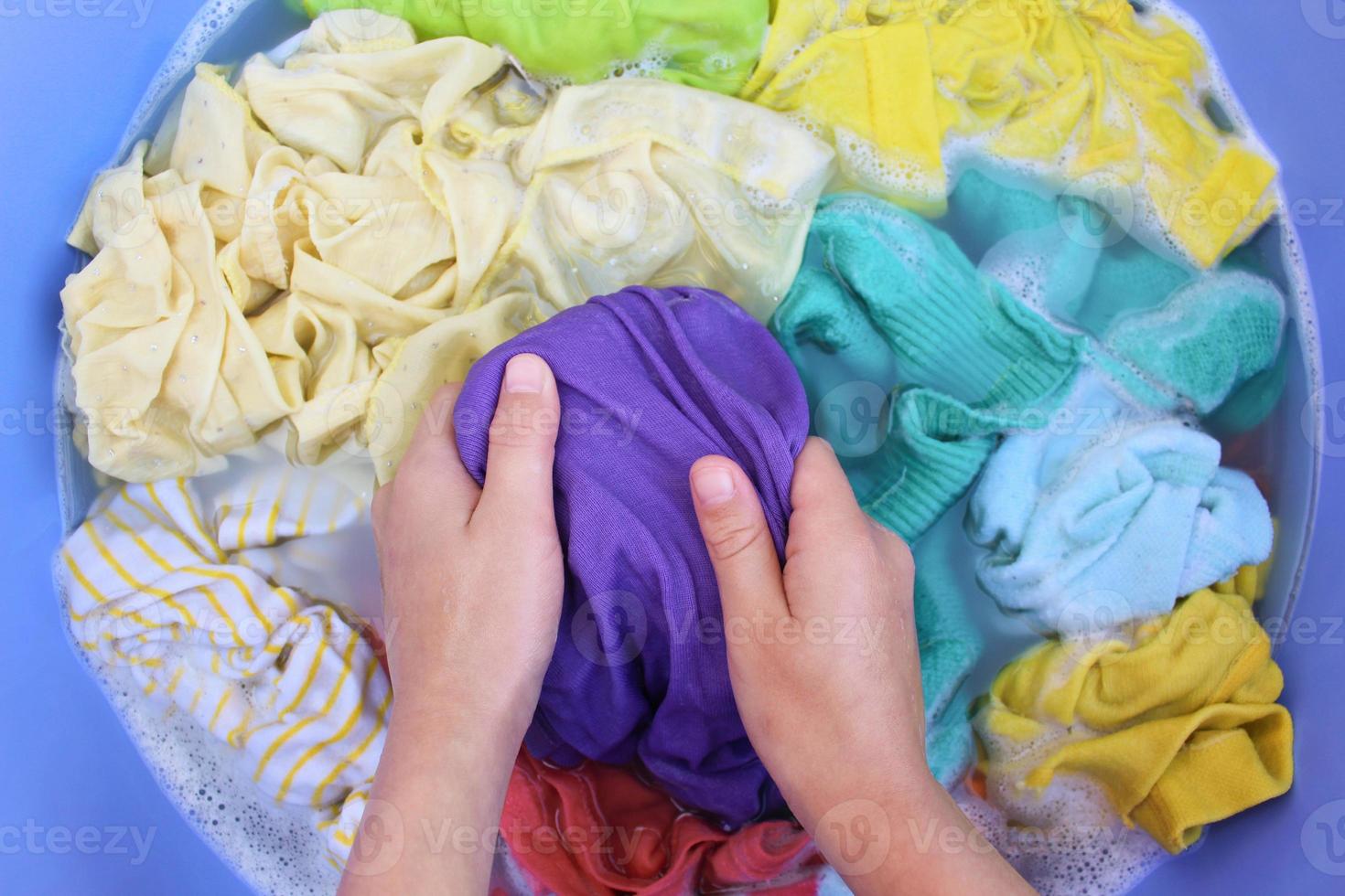 vrouw handen wassen gekleurde kleren in bassin. top visie. foto