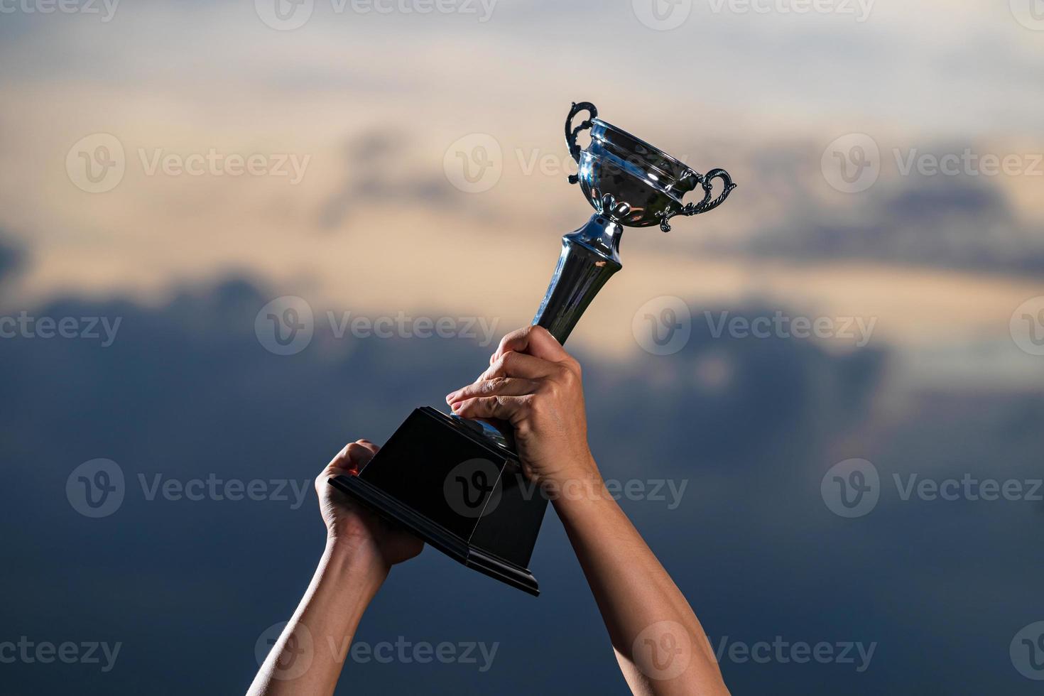 een man die een trofeekop tegen de bewolkte hemelachtergrond van de schemering houdt foto