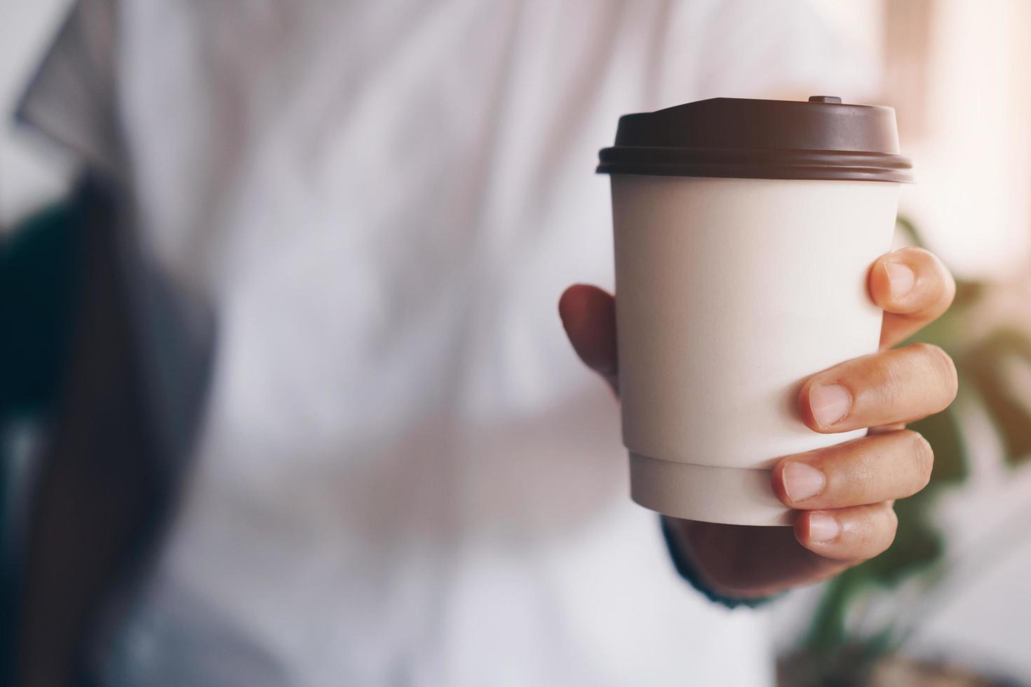 hand met een kopje koffie met zonlicht flare foto