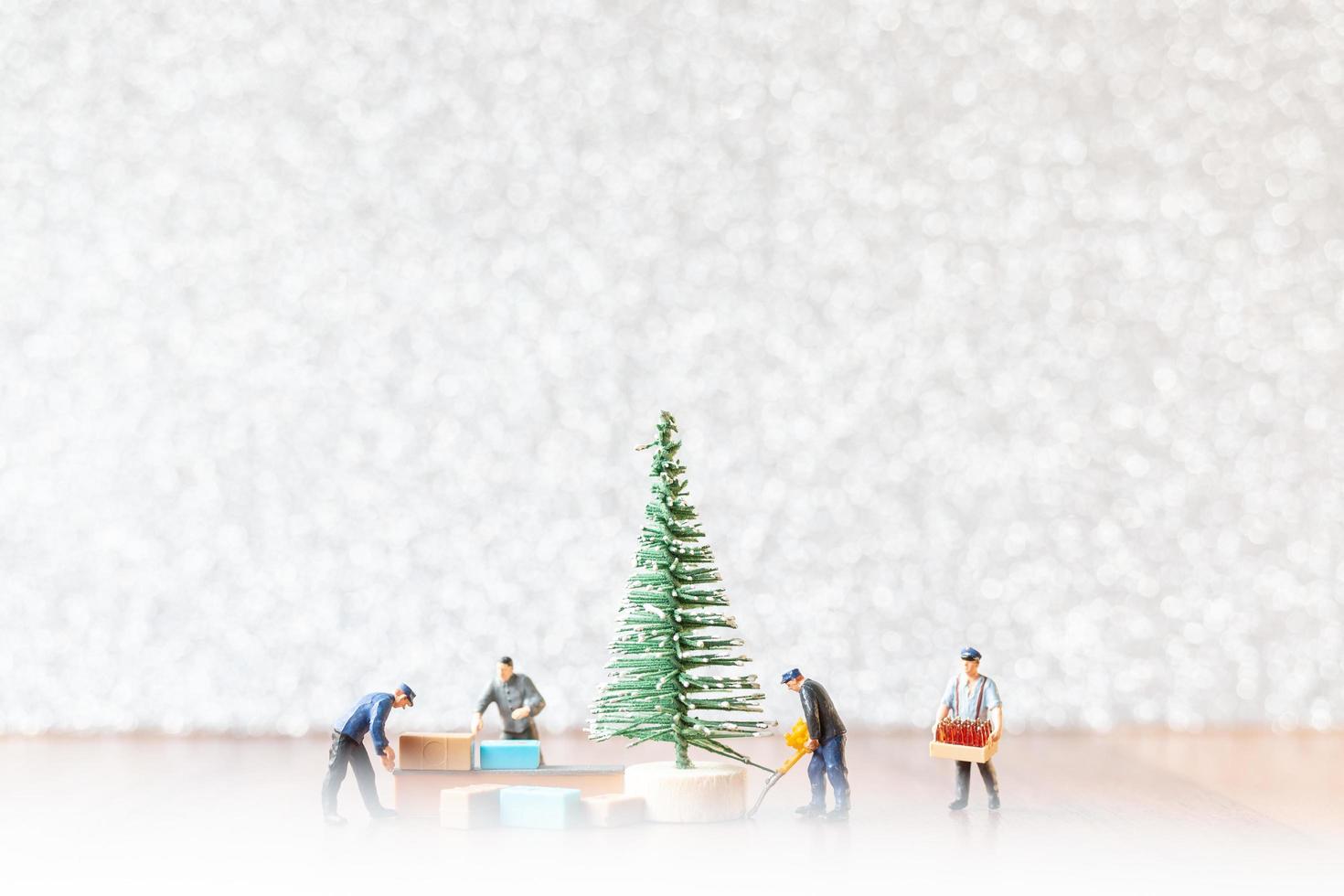 groep miniatuurarbeiders die een kerstboom voorbereiden, het concept van kerstversieringen foto