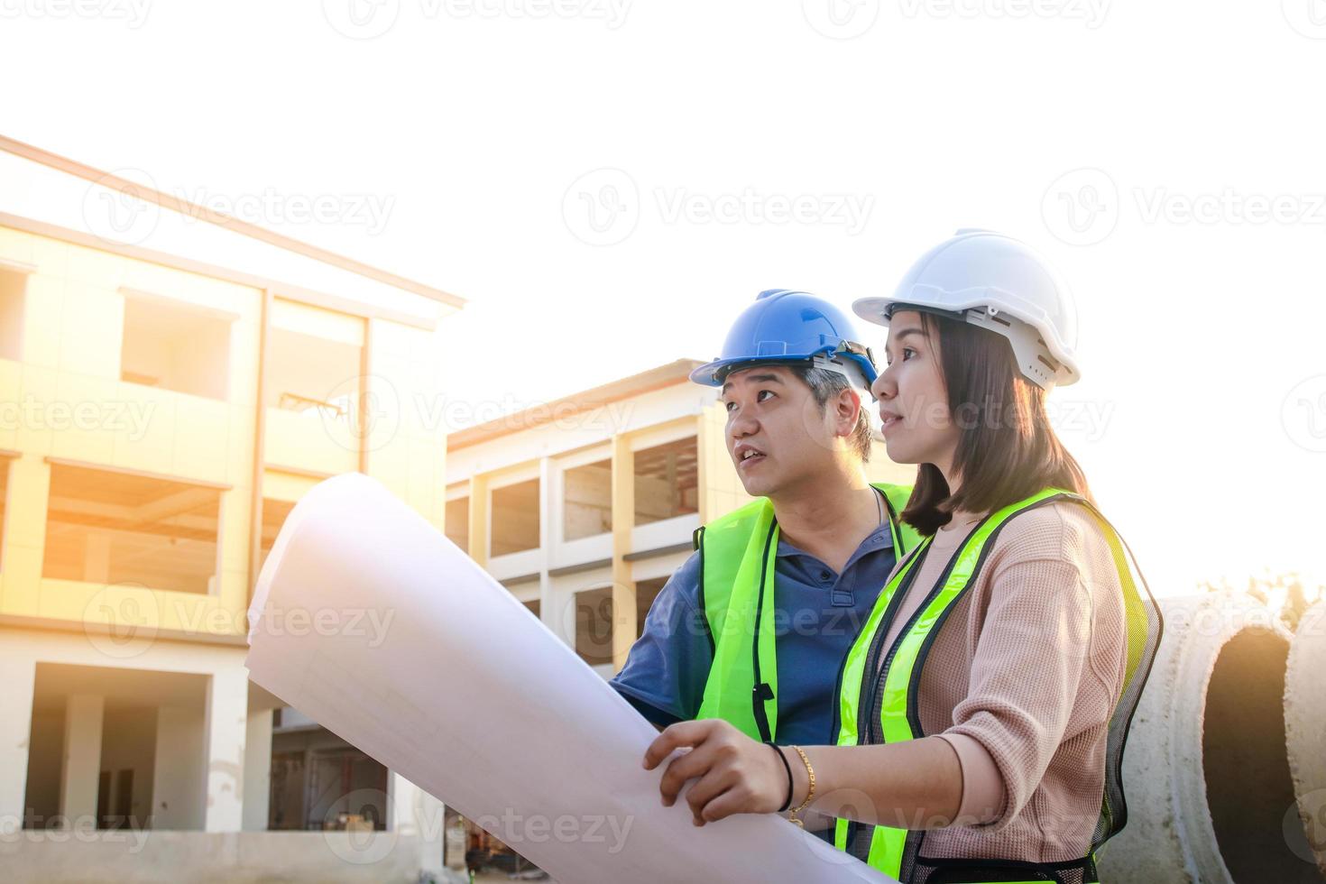 ingenieurs en architecten, mannen en Dames, kijken Bij de gebouw blauwdruk naar controleren de nauwkeurigheid van de bouw. foto