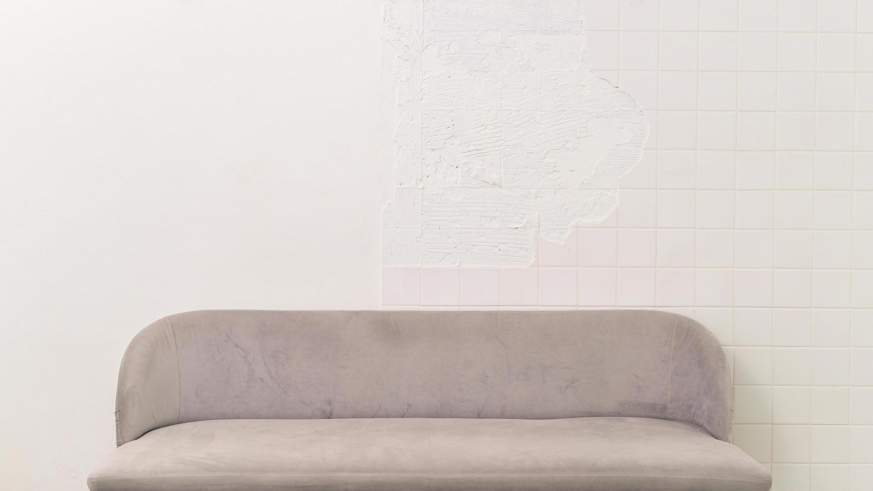 grijs zacht comfortabel knus minimalistische sofa elegant binnen- interieur meubilair kamer, bankstel decor ontwerp van wit steen huis muur achtergrond. modern leeg ruimte backdrop in leven appartement huis stijl. foto