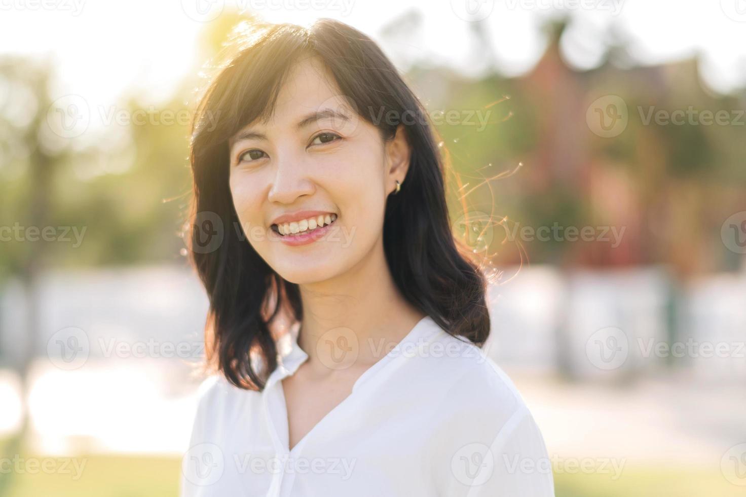 portret jong mooi Aziatisch vrouw met gelukkig glimlach in de omgeving van buitenshuis park in zonnig zomer dag foto