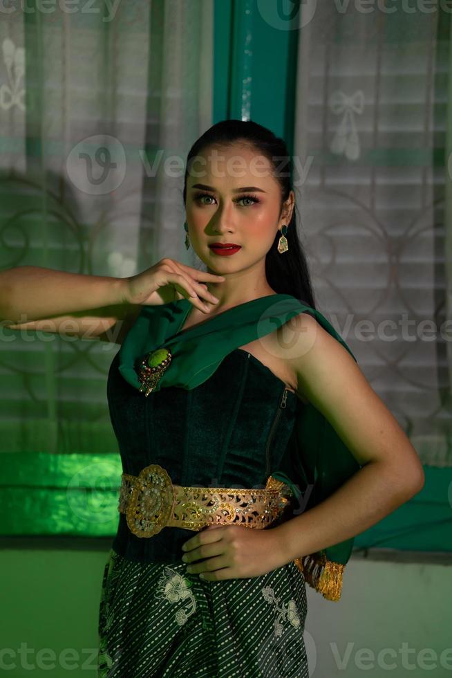 een vrouw balinees danser gekleed allemaal in groen poses heel sexy in een groen kamer foto