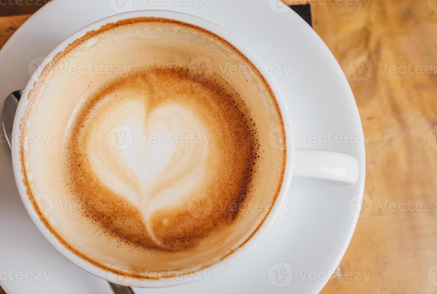 dichtbij omhoog van de latte kunst in hart vorm Bij de bodem van een kop van heet koffie. foto