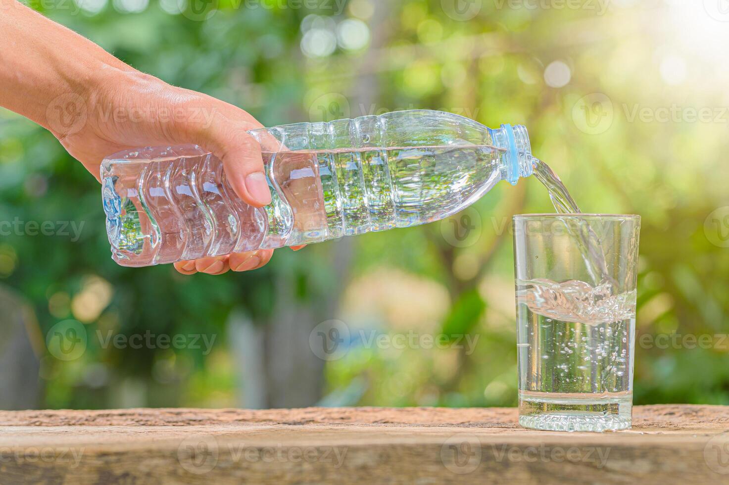 fles drinkwater en glas met natuurlijke achtergrond foto