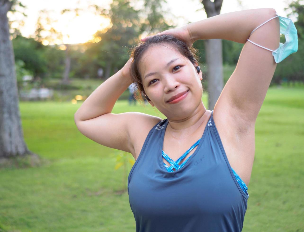 portret van een mooi Aziatisch vrouw in sportkleding, staand met haar rug, uitrekken voordat oefenen buitenshuis in de park in de ochtend- naar bereiken een gezond levensstijl. gezond opwarming omhoog foto