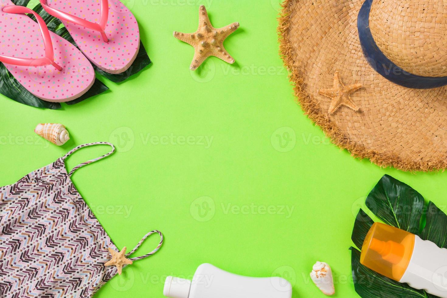 zomer accessoires met t-shirt, schelpen, omdraaien flops zonnescherm fles en rietje hoed Aan groen achtergrond top visie vlak leggen foto