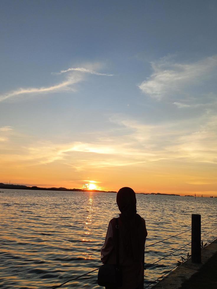 moslim hijab genieten van de zonsondergang Aan de strand foto