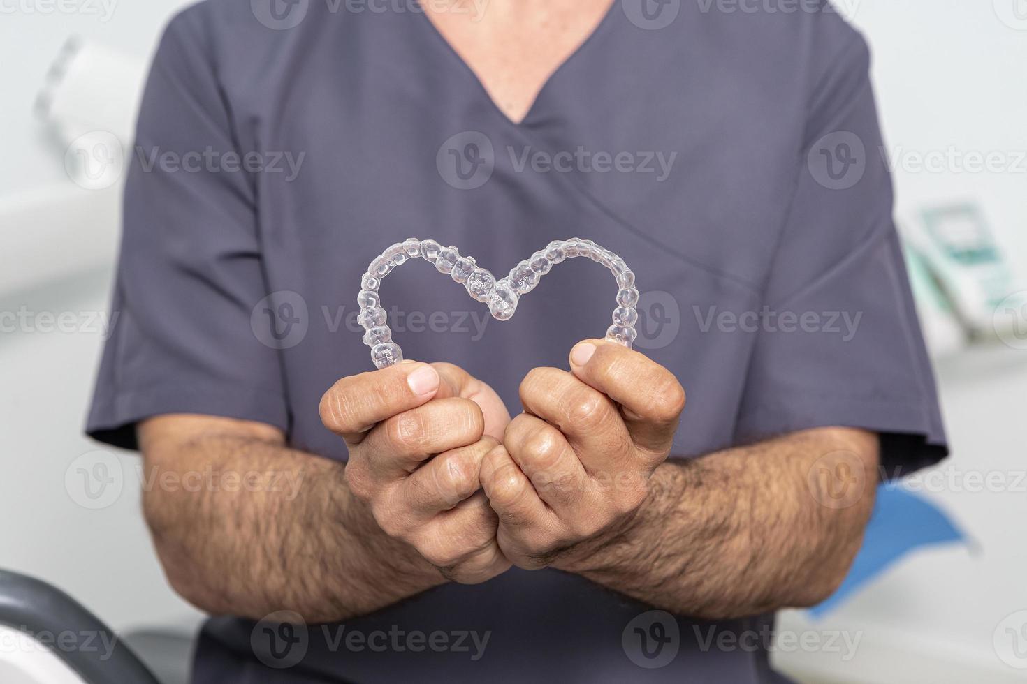 Bijsnijden anoniem stomatoloog tonen hart gemaakt met aligners foto