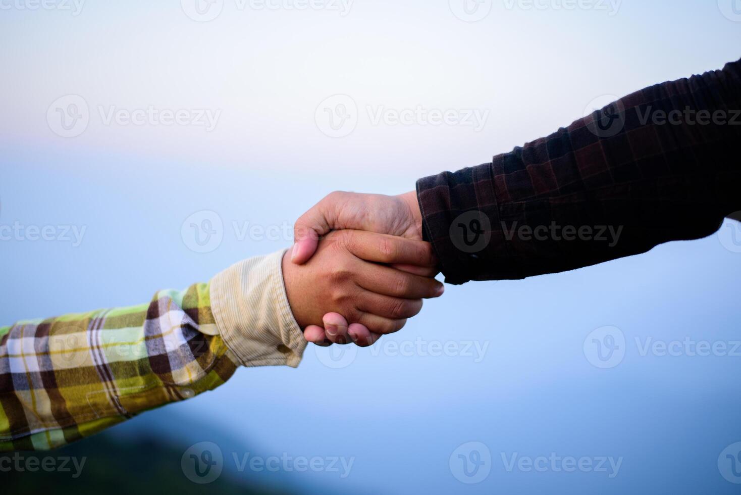 detailopname hand- van twee mannetje wandelaars helpen elk andere beklimmen omhoog een berg foto