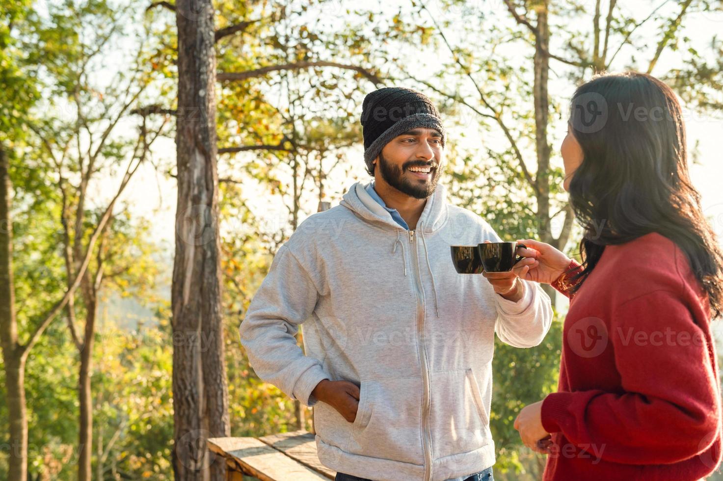 gelukkig reiziger paar resting Aan bergen in zonsopkomst met drinken koffie foto