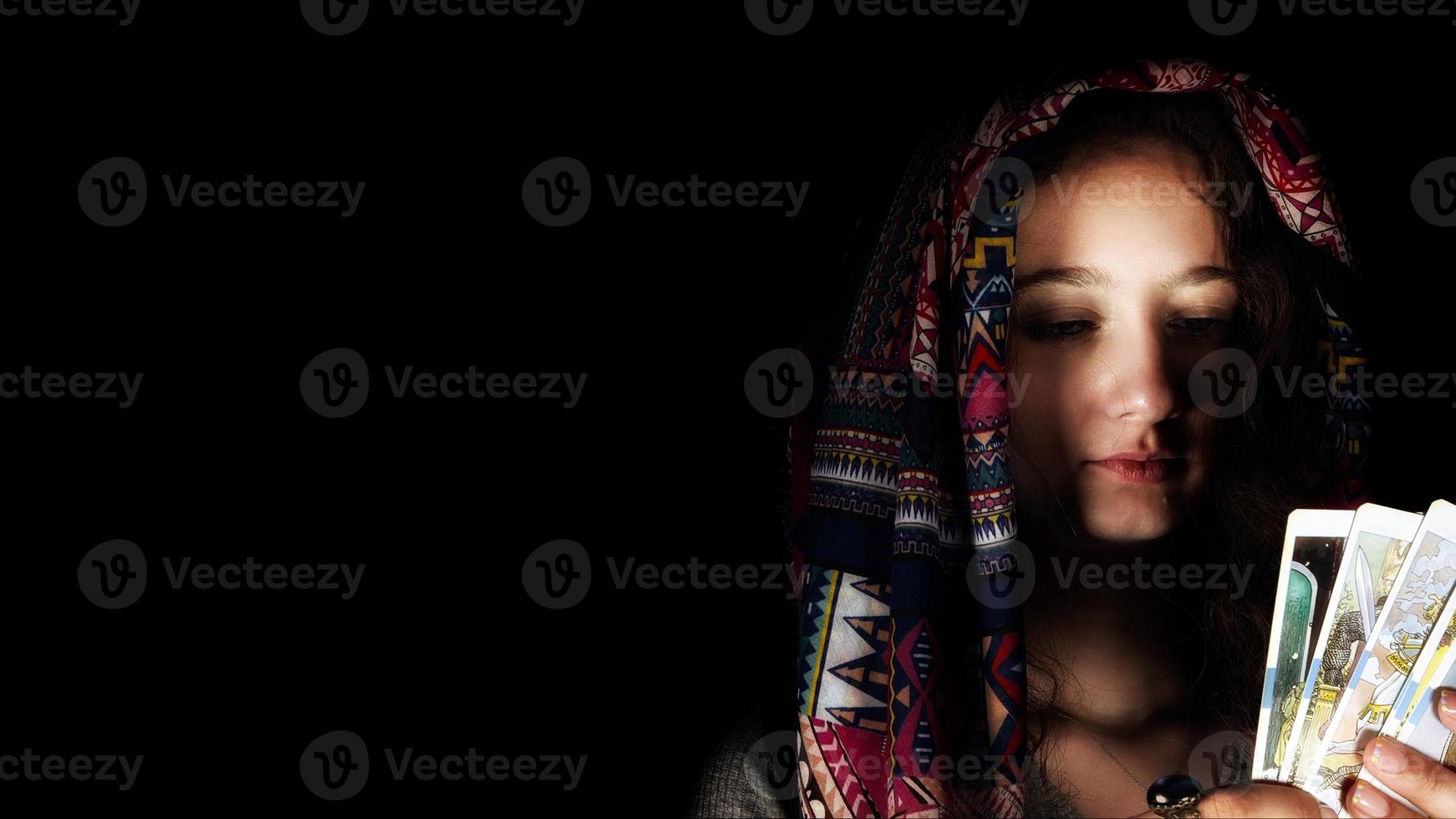jong meisje in hoofddoek houding Holding tarot kaarten foto