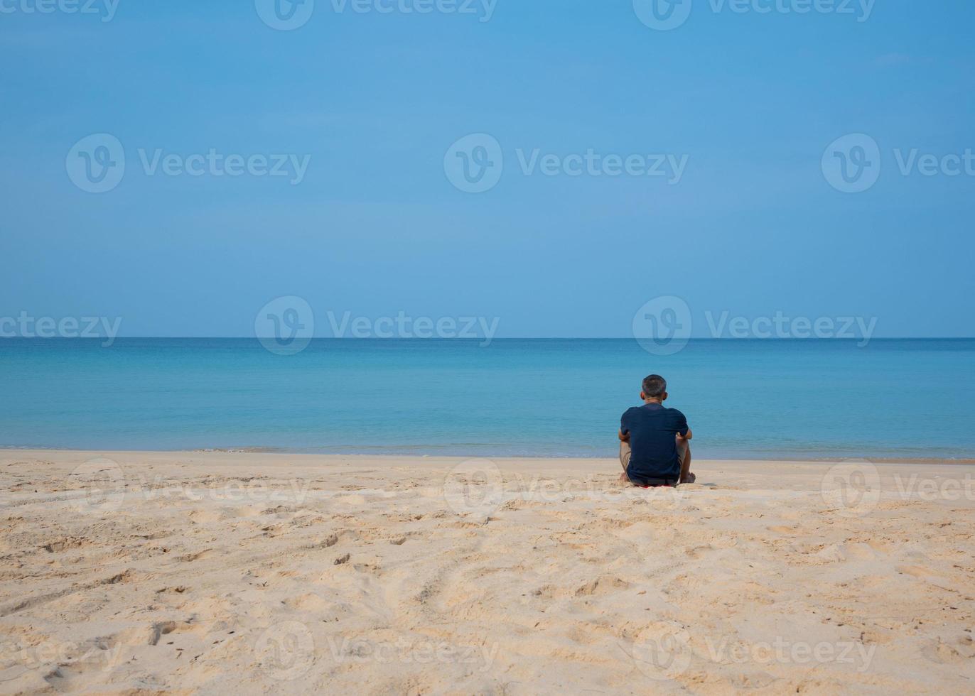 een senior Aziatisch mannetje zittend Aan de strand foto