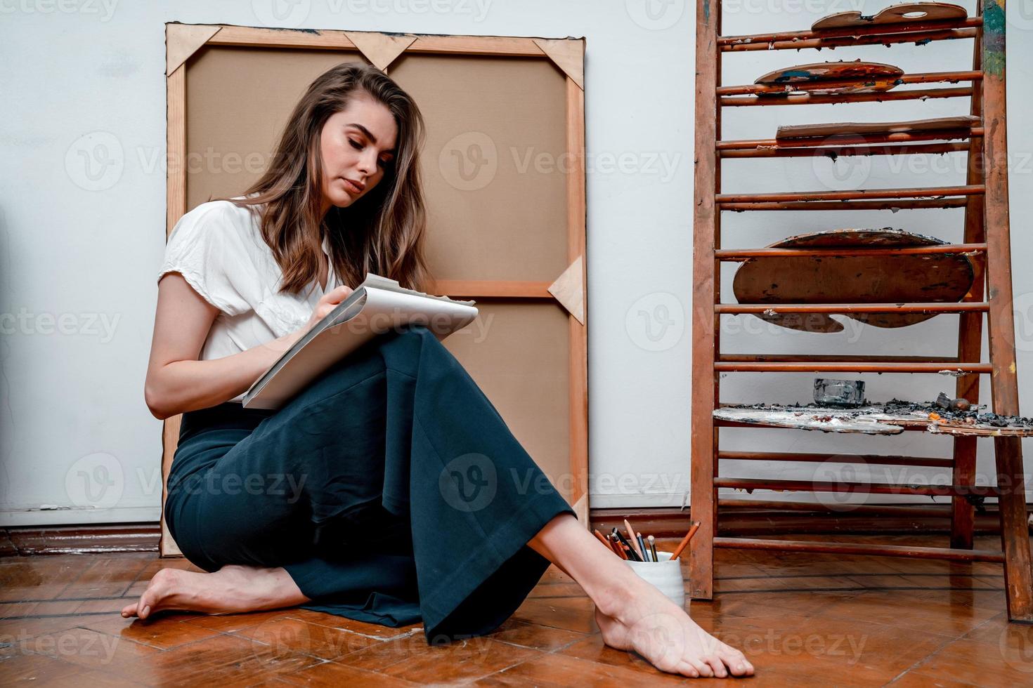 portret van een mooi jong artiest, trekt afbeeldingen in de werkplaats foto