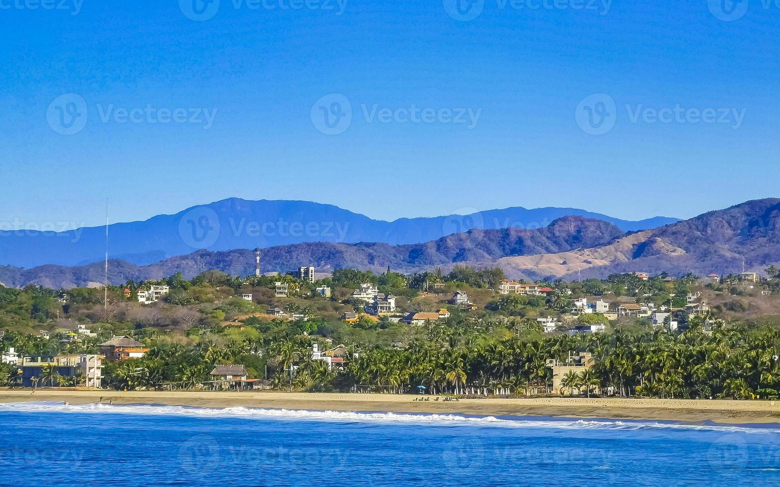 zon strand kliffen rotsen golven palmen bergen puerto escondido Mexico. foto
