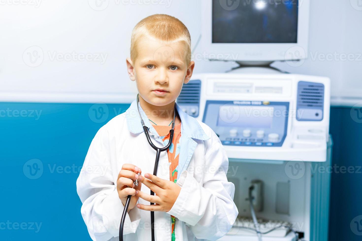 glimlachen weinig jongen in medisch uniform spelen met stethoscoop foto