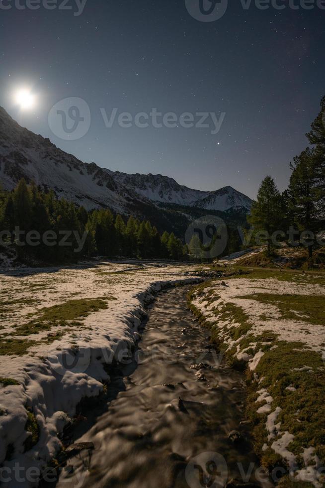een stroom in de bergen gedurende een vol maan nacht foto
