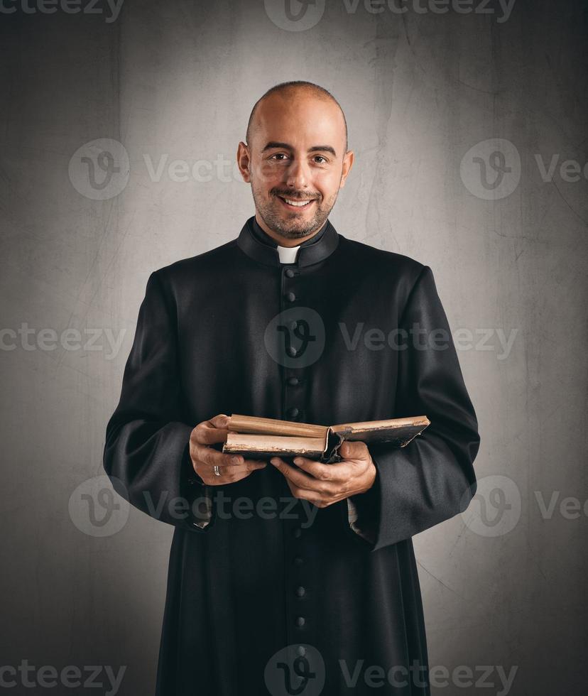priester glimlachen en Holding een Bijbel foto