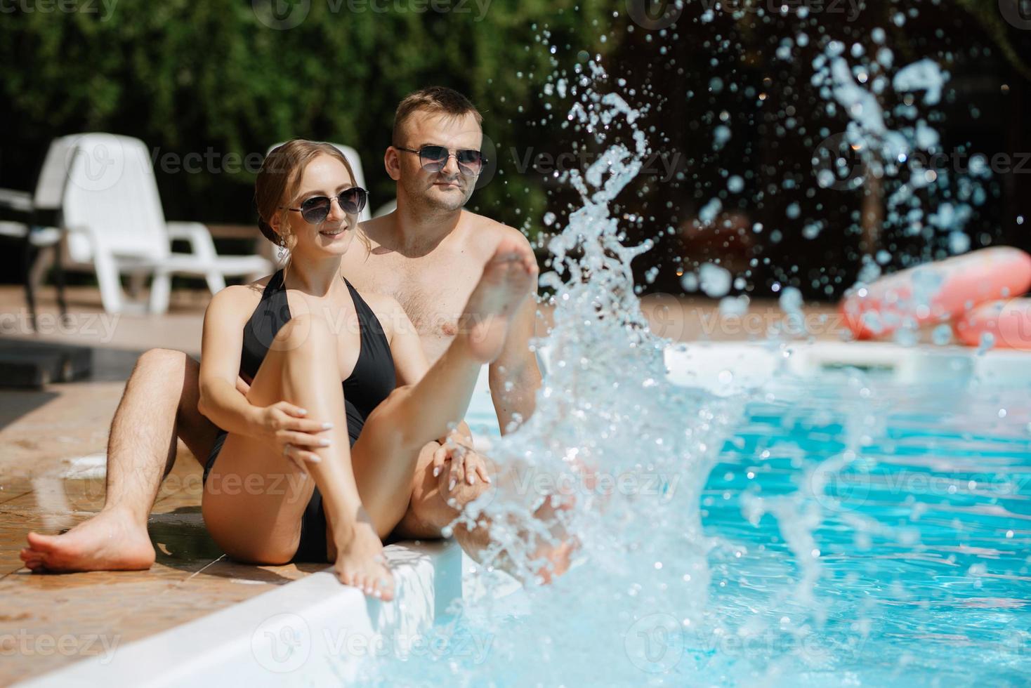 vent en een meisje in het baden pakken zijn ontspannend, in de buurt de blauw zwembad foto