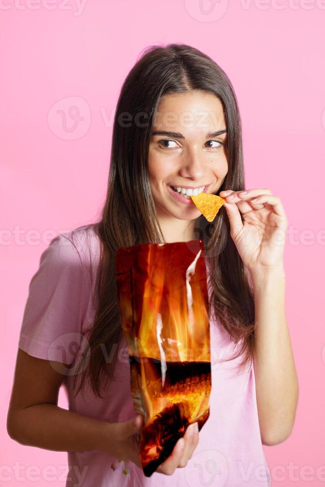 vrouw in roze t overhemd aan het eten chips foto