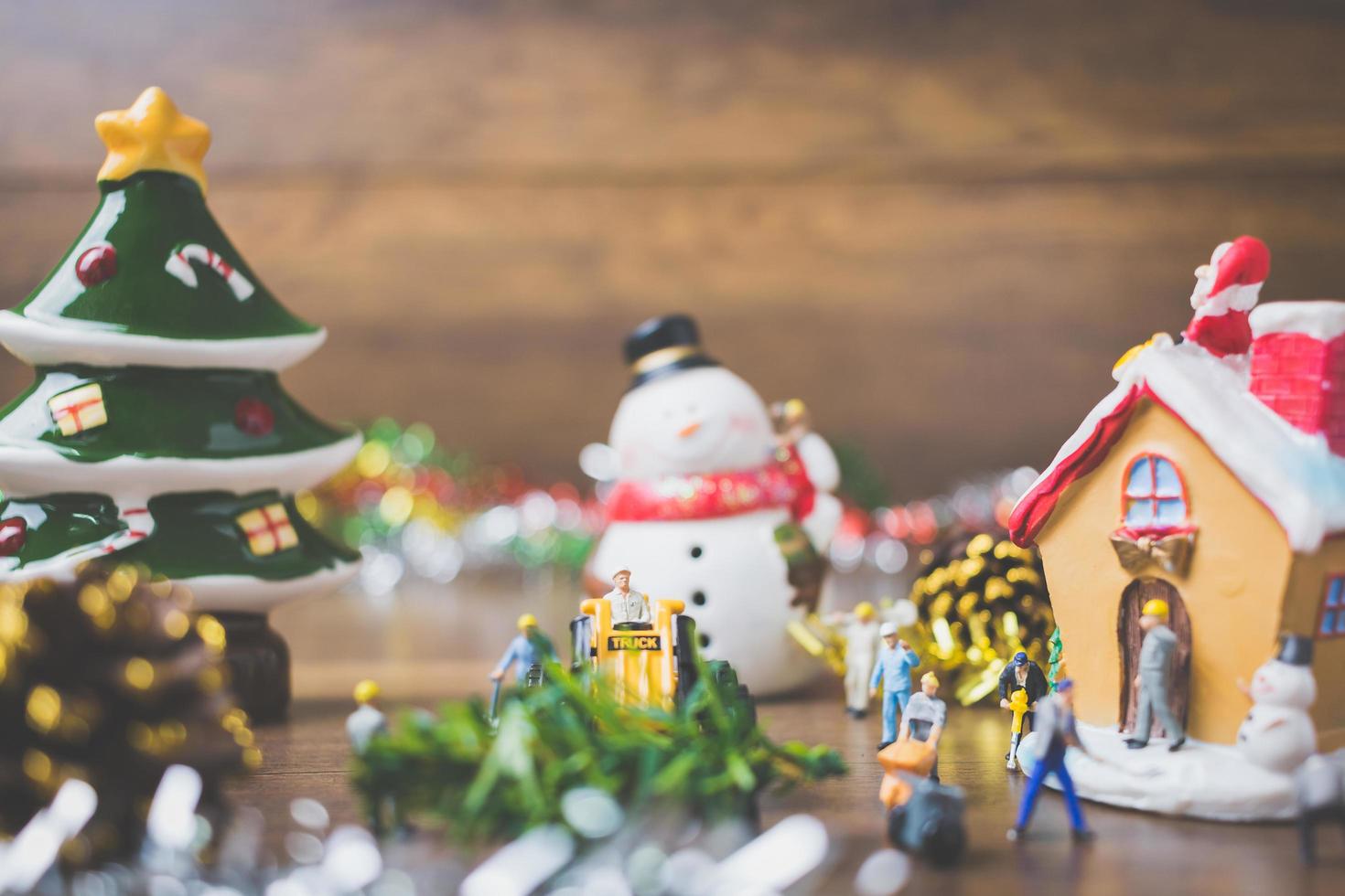 miniatuurmensen die kerstversieringen maken op een houten achtergrond foto