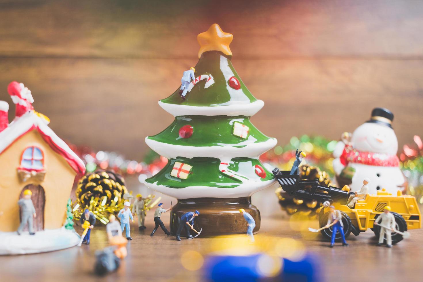 miniatuurmensen die kerstversieringen maken op een houten achtergrond foto