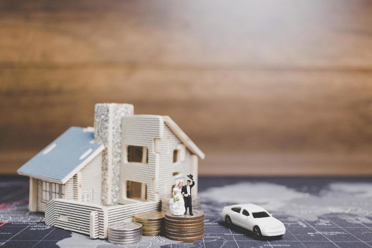 miniatuurbruid en bruidegom met muntstukken voor een huis, succesvol familieconcept foto