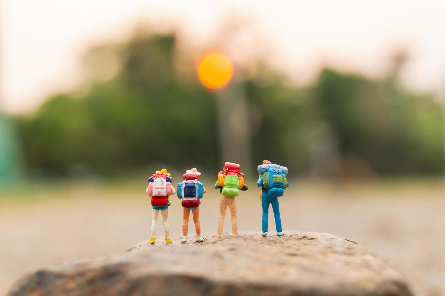 miniatuurreizigers met rugzakken die op een rots-, reis- en avontuurconcept lopen foto