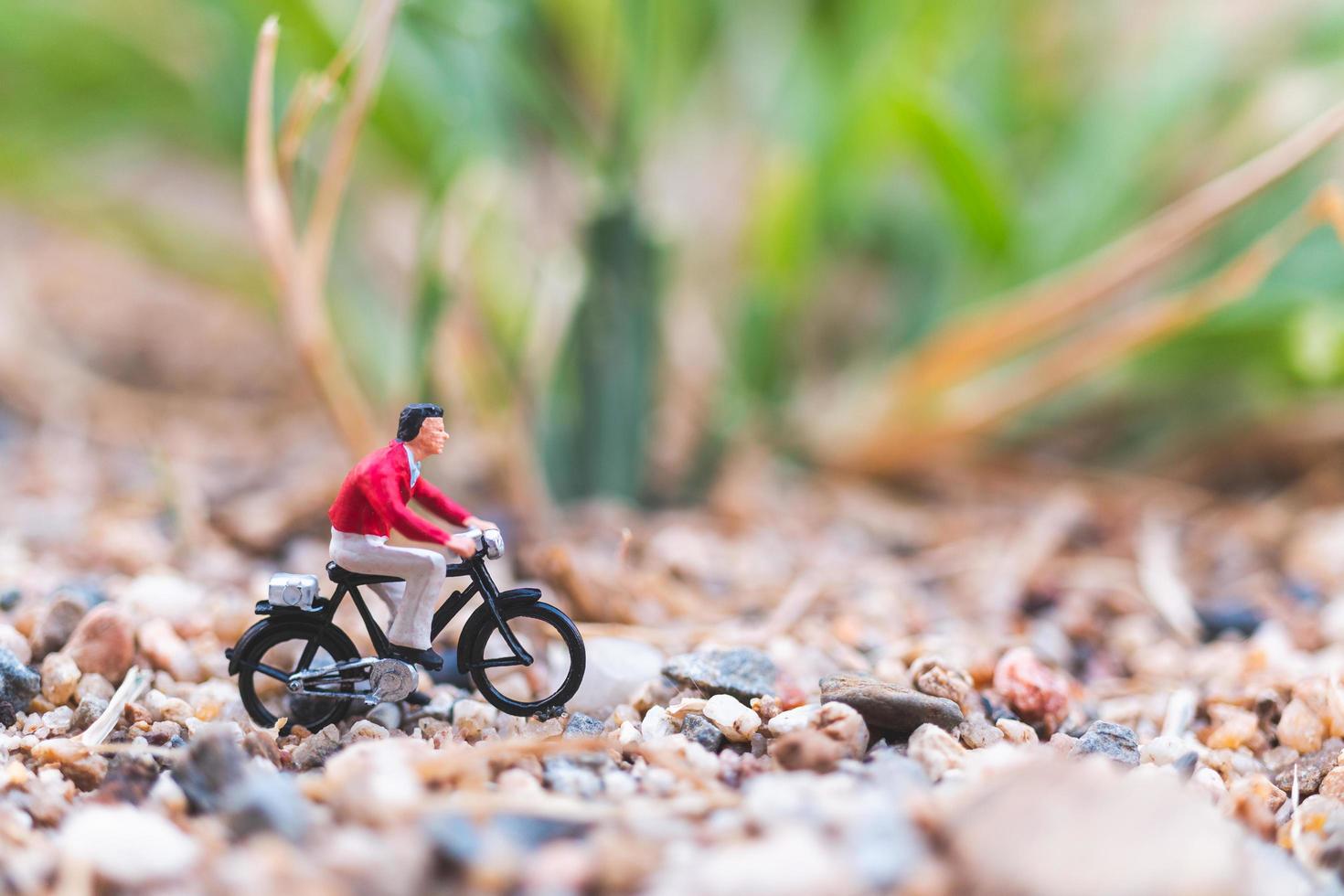 miniatuurreiziger die een fiets berijdt, het wereldconcept onderzoekt foto