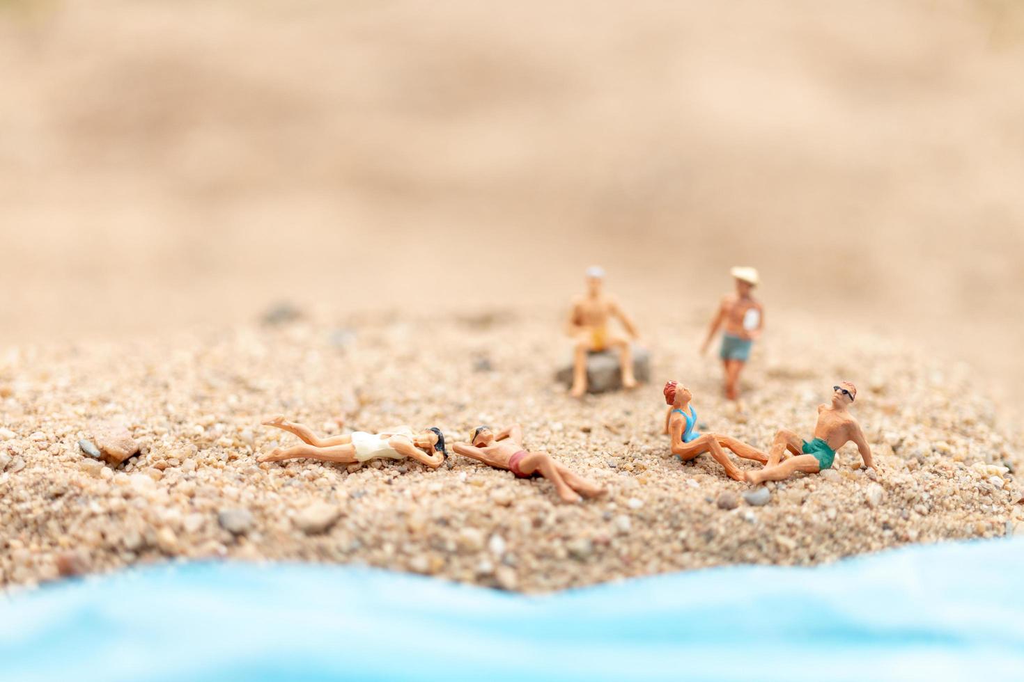 miniatuurmensen die zwemkleding dragen die op een strand, de zomerconcept ontspannen foto