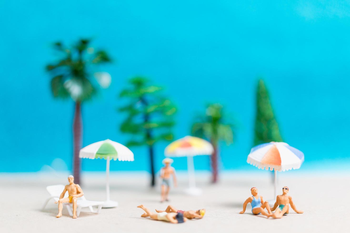 miniatuurmensen die zwemkleding dragen die op een strand, de zomerconcept ontspannen foto